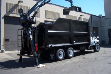 Rear-mounted Serco 8500 series loader, 8,500 lbs capacity, 25 ft tele-boom with brush grapple