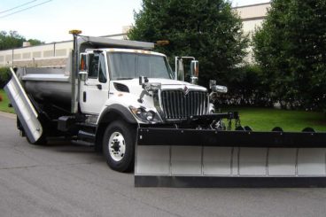 Single axle snow plow truck with stainless steel body, spreader, wing, and plow.