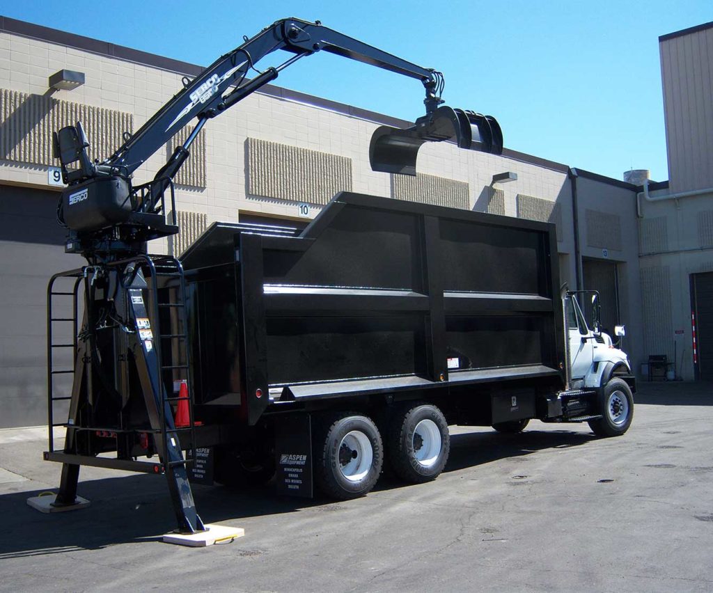 Rear-mounted Serco 8500 series log loader, 8,500 lbs capacity, 25 ft tele-boom with brush grapple