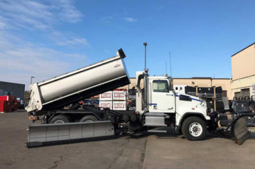 Tandem axle plow truck with stainless steel body, plow, wing, and salt/sand spreader