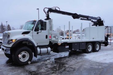 Rear-mounted Serco 8500 material grapple loader with flatbed body