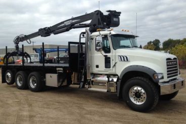 Behind-cab mounted Serco 8500 loader with pole grapple and flatbed body