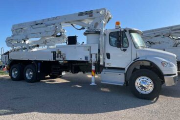 White industrial concrete boom pump truck parked on a gravel lot. Boom says EVERDIGM and 33ZX. A yellow signal light is on the cab.