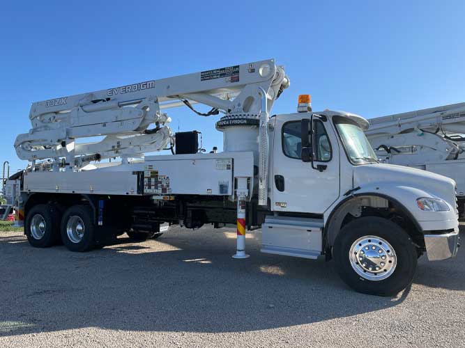 White industrial concrete boom pump truck parked on a gravel lot. Boom says EVERDIGM and 33ZX. A yellow signal light is on the cab.