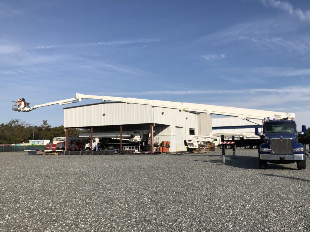 Demonstration of Bronto Skylift S-XDT model aerial work platform with telescopic cage boom extended horizontally in front of an industrial building.