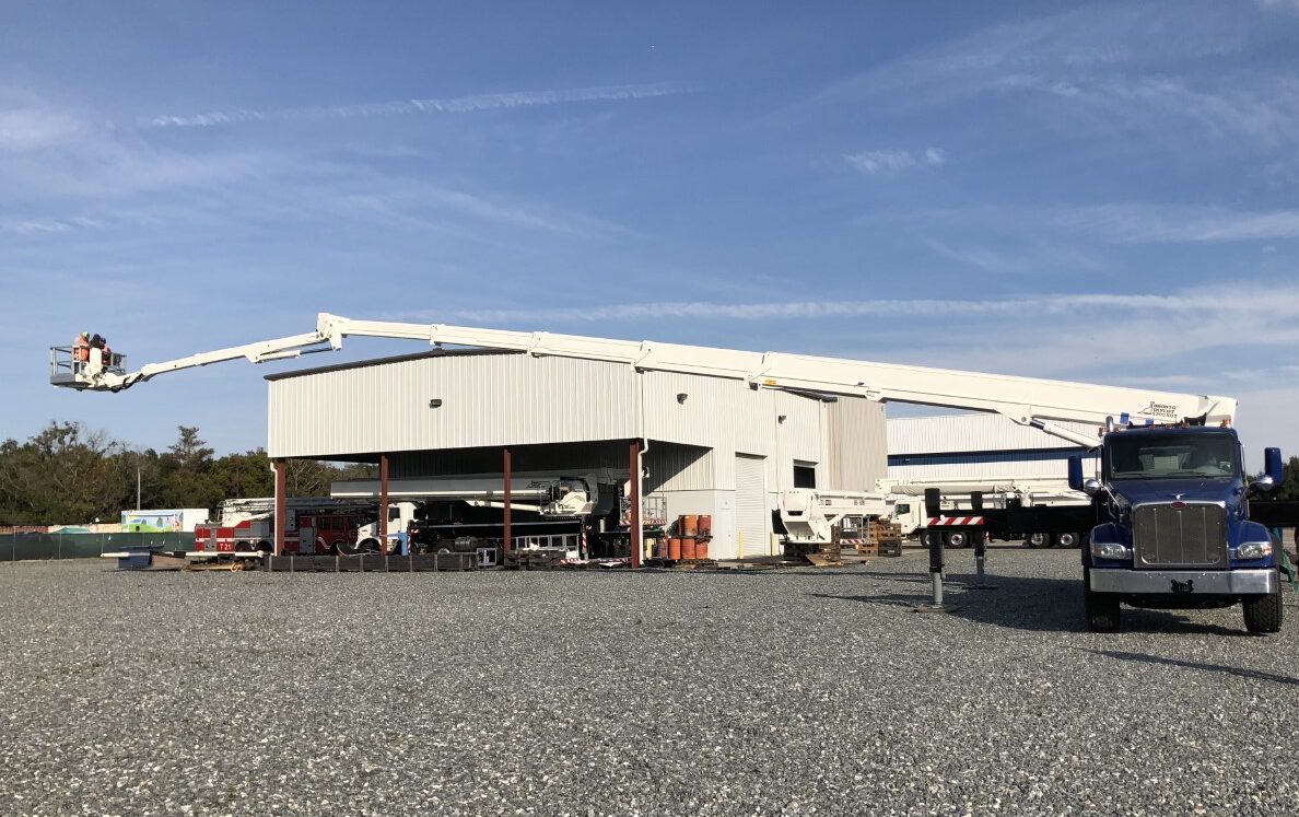 Demonstration of Bronto Skylift S-XDT model aerial work platform with telescopic cage boom extended horizontally in front of an industrial building.