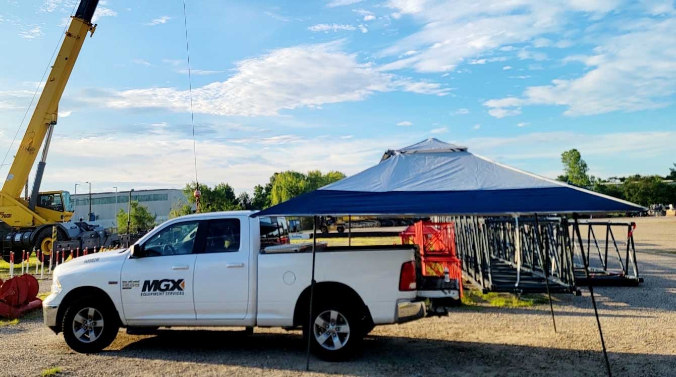 Outdoors picture of MGX Equipment Services field service truck with Grove rough terrain crane and uninstalled lattice jibs on the ground