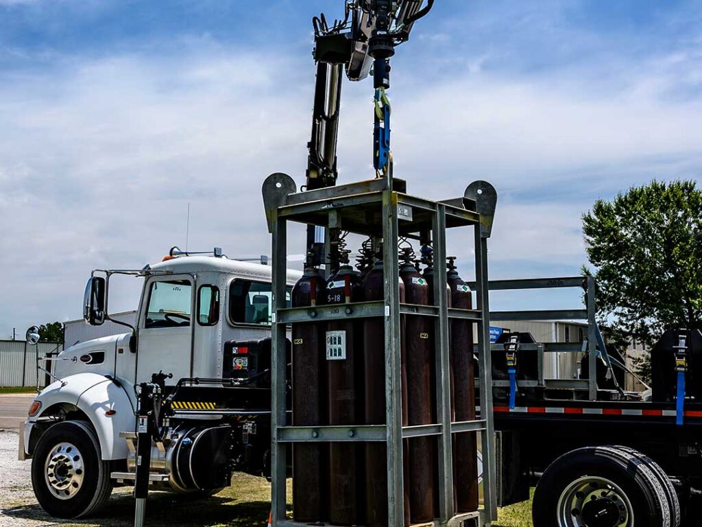Flatbed work truck with HIAB heavy-duty knuckle boom crane parked in the driveway with extended boom over the roof of a home.