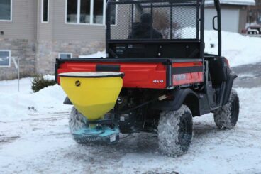 UTV with FISHER tailgate salt spreader outside residential homes.