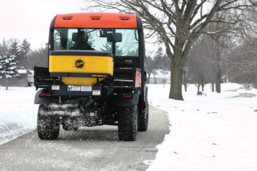 UTV with FISHER poly tailgate spreader driving on a walking path.