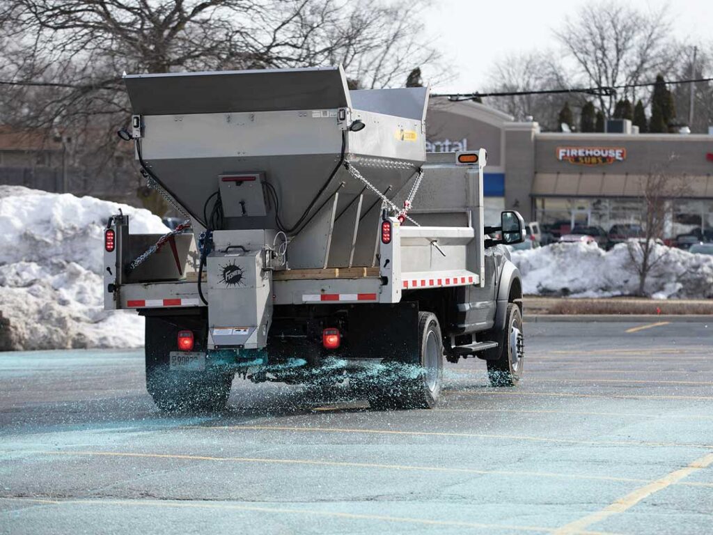 UTV with FISHER poly tailgate spreader driving on a walking path.
