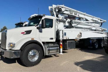 White concrete boom pump truck on Peterbilt cab tandem axle chassis