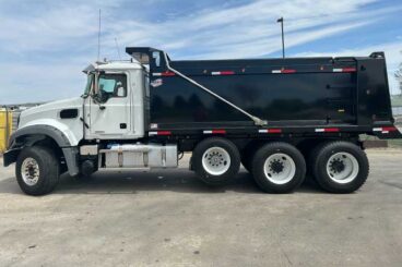 MAXX brand dump body mounted on white heavy-duty Mack standard cab chassis parked on a paved lot. Features tandem rear axles with pusher.