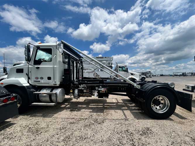 Mack MD7 chassis truck upfitted with SwapLoader hooklift system parked under blue skies for heavy-duty commercial use in construction, waste, and municipal fleets.