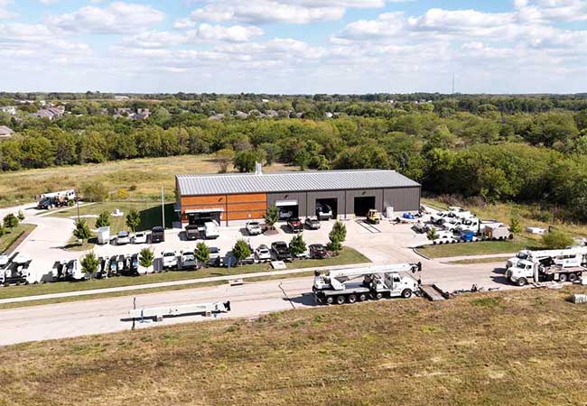 Aerial picture of boom trucks, cranes, and work truck equipment outside a modern MGX facility in Kansas City