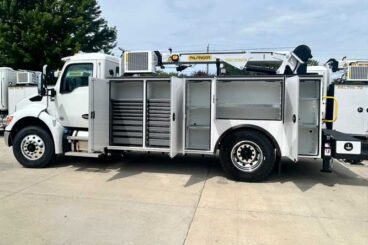 Large white work truck with mechanics body parked outdoors on concrete. Compartment doors opened showing shelves and drawers. Compressor and service crane labeled with Palfinger logo and PSC 10829 mounted on truck body.
