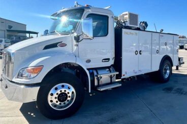 White Peterbilt commercial work truck with Palfinger PAL Pro 72 mechanics body and rotary screw compressor parked outdoors under sunny, cloudless blue skies.