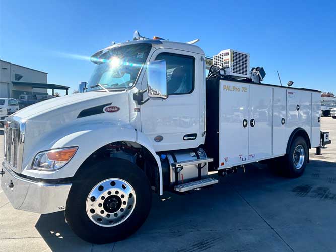 White Peterbilt commercial work truck with Palfinger PAL Pro 72 mechanics body and rotary screw compressor parked outdoors under sunny, cloudless blue skies.